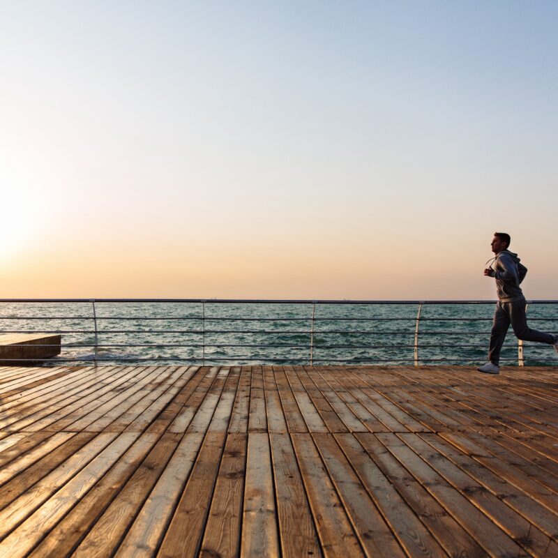 Man running on boardwalk alongside water