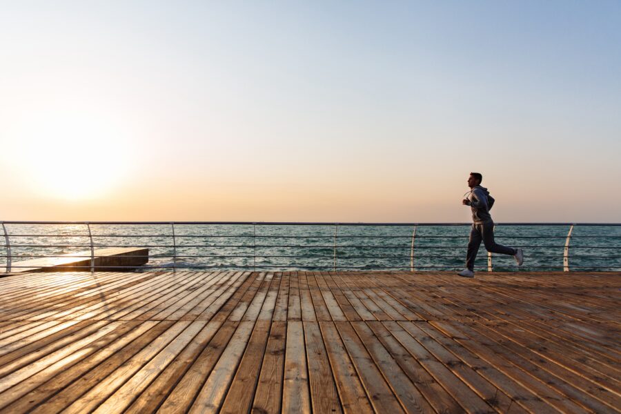 Man running on boardwalk alongside water