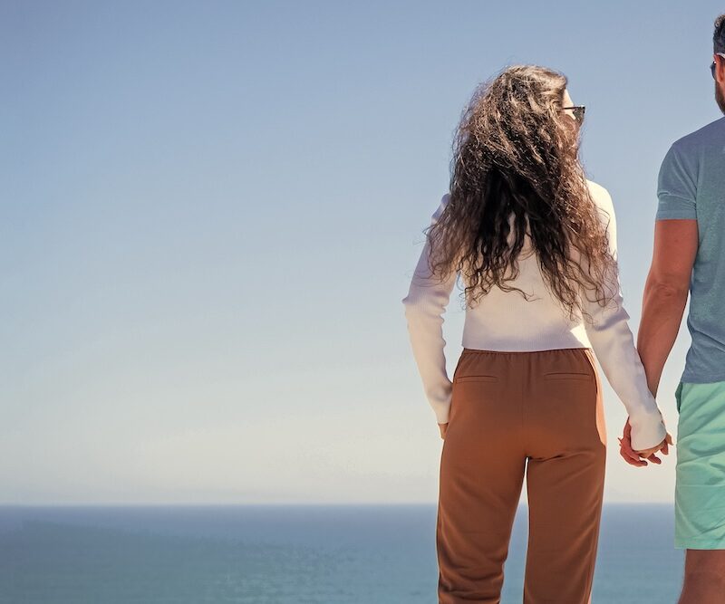 fit couple holding hands looking at the water