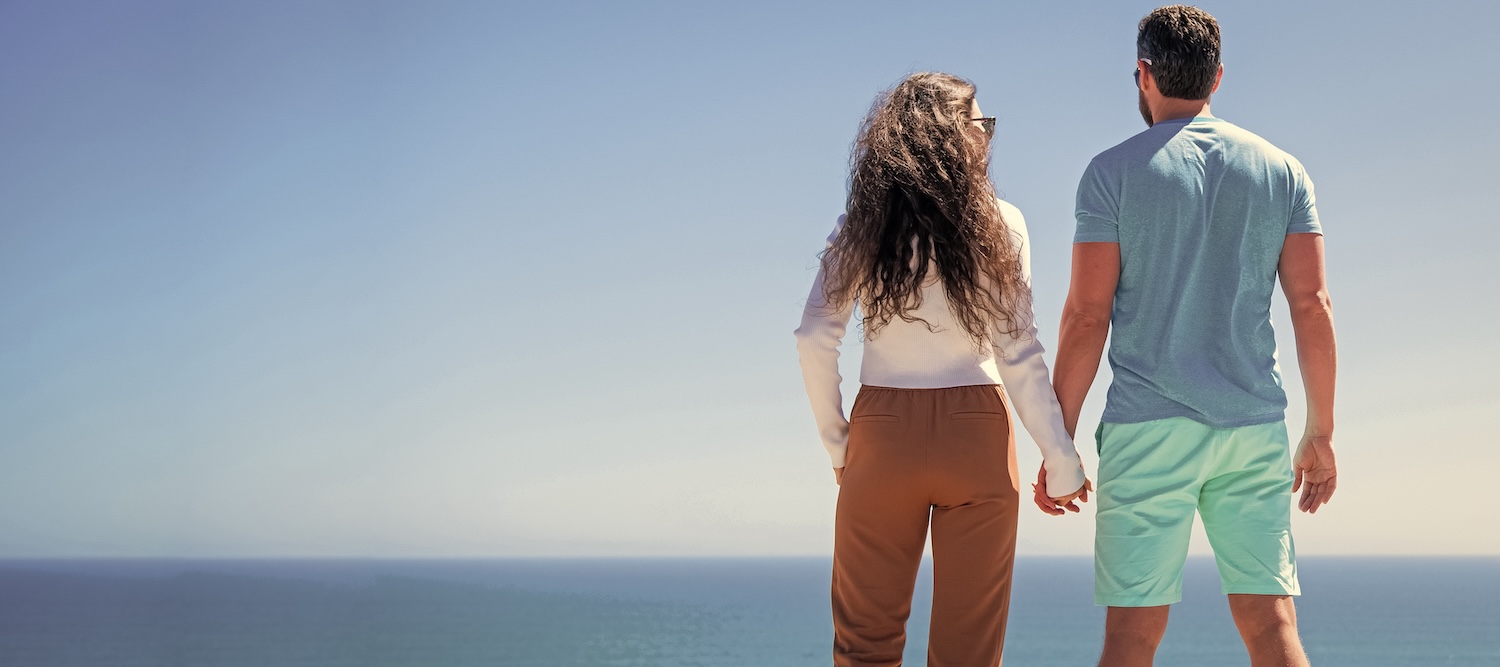 fit couple holding hands looking at the water